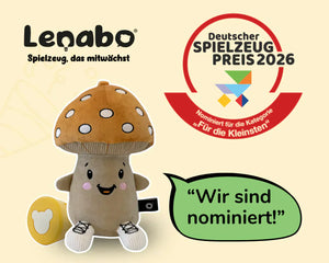 Lenabo Kuscheltier (Lenabie) in Pilzform mit Smart Toy System neben Logo „Deutscher Spielzeugpreis 2026“ und Hinweis auf Nominierung in der Kategorie „Für die Kleinsten“, inklusive Slogan „Spielzeug, das mitwächst“ und Text „Wir sind nominiert!“