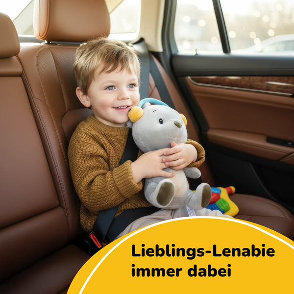 Kleinkind im Autositz hält Lenabie Aaron (Bär) im Arm – mobiles Hörspiel-Kuscheltier aus dem Lenabo Starter Kit mit herausnehmbarem Smart Speaker und 60+ Minuten Audio-Spielzeit für unterwegs.
